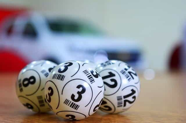 Three white bingo balls with black numbers on them, on a table.