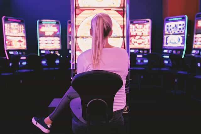 A woman sitting in front of a series of casino video betting machines.