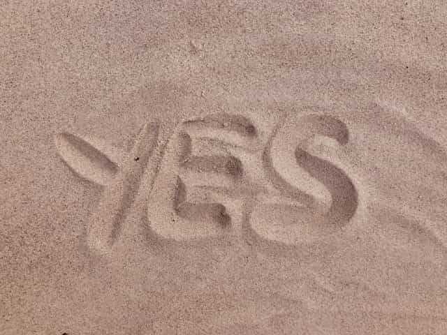 The word “yes” drawn into the sand on a beach or in a desert.