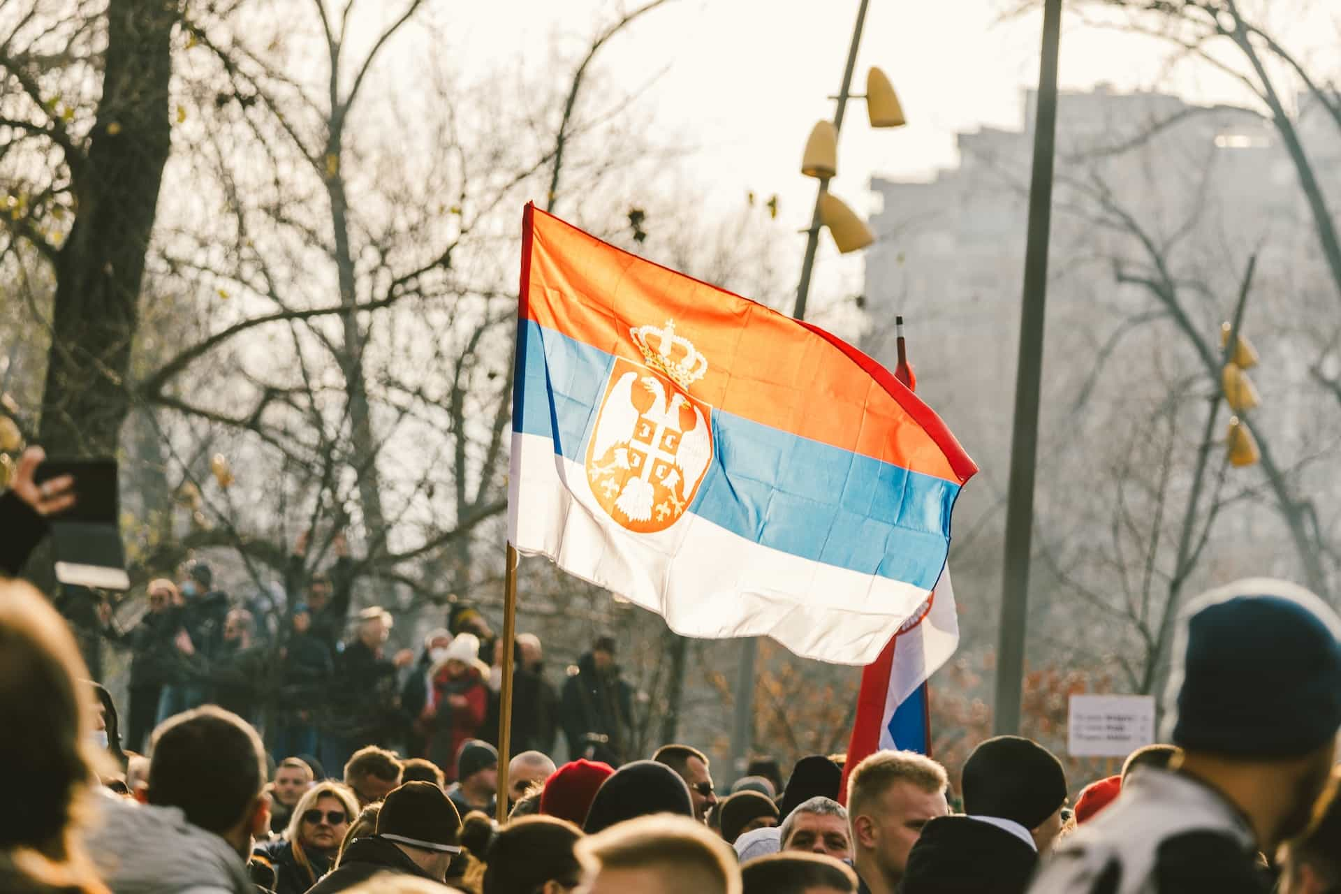 A crowd of people standing around a red, blue, and white flag.