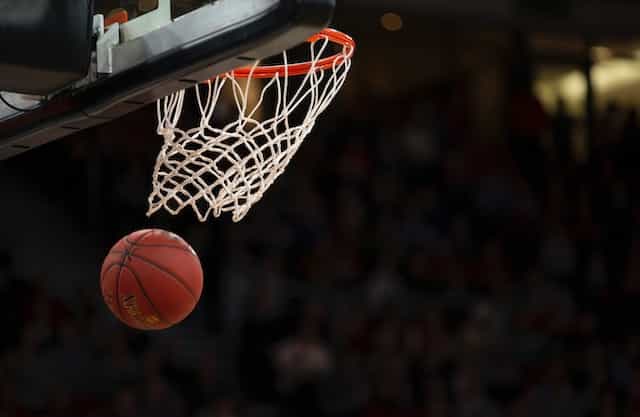 A basketball swishing through the net of a hoop during a game as a result of a player throwing it in and scoring a point.