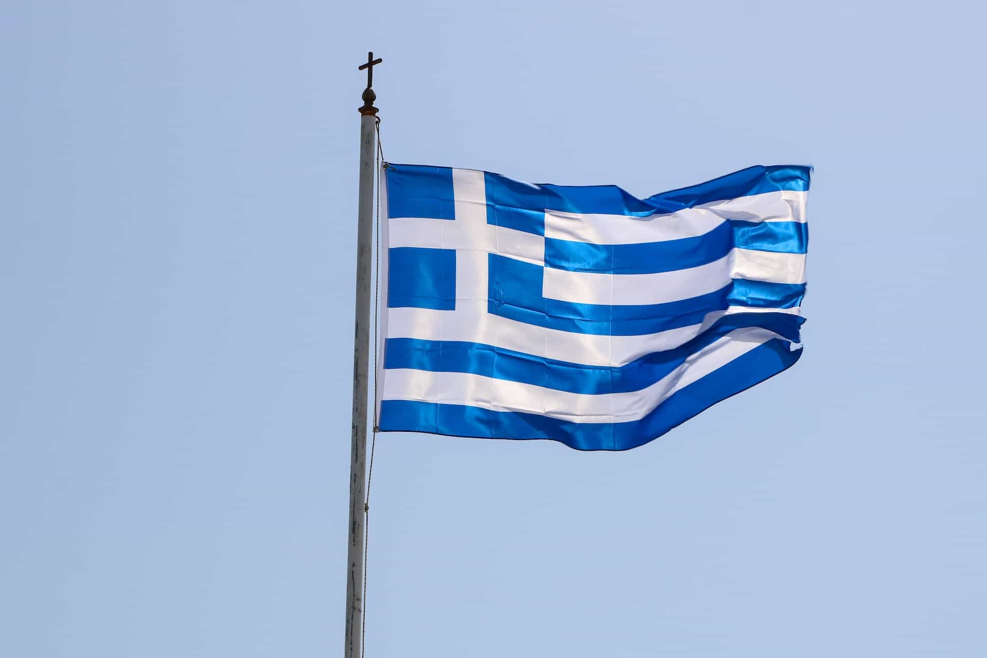 A blue and white flag against the blue sky.