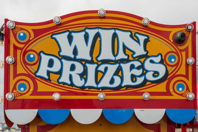 A carnival sign reads WIN PRIZES in yellow and red paint.