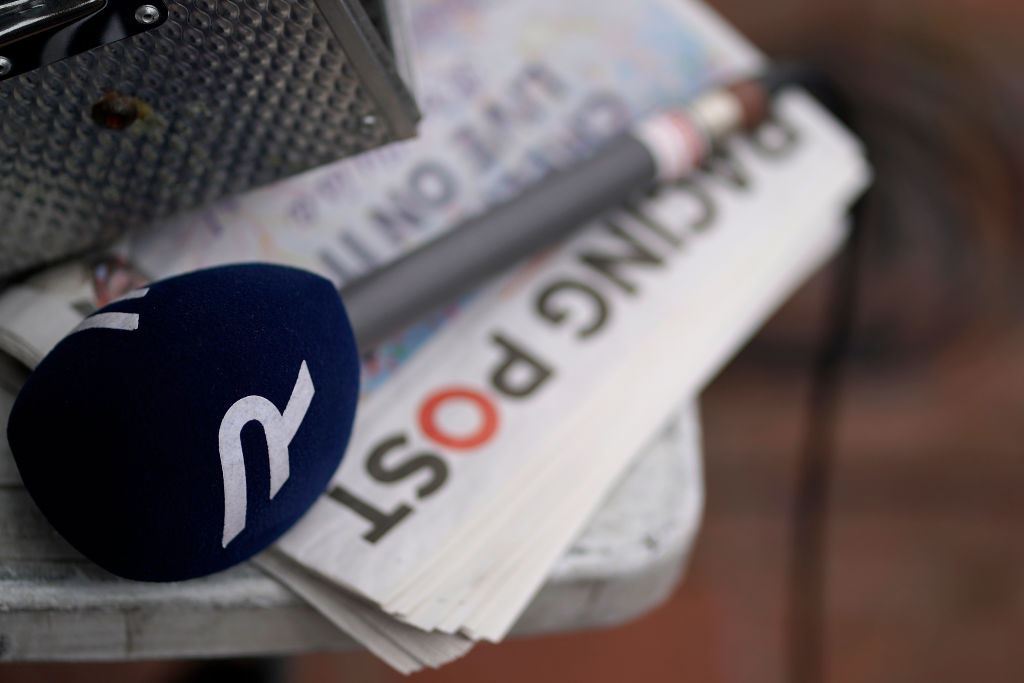 A Racing TV microphone sits on a Racing Post newspaper.