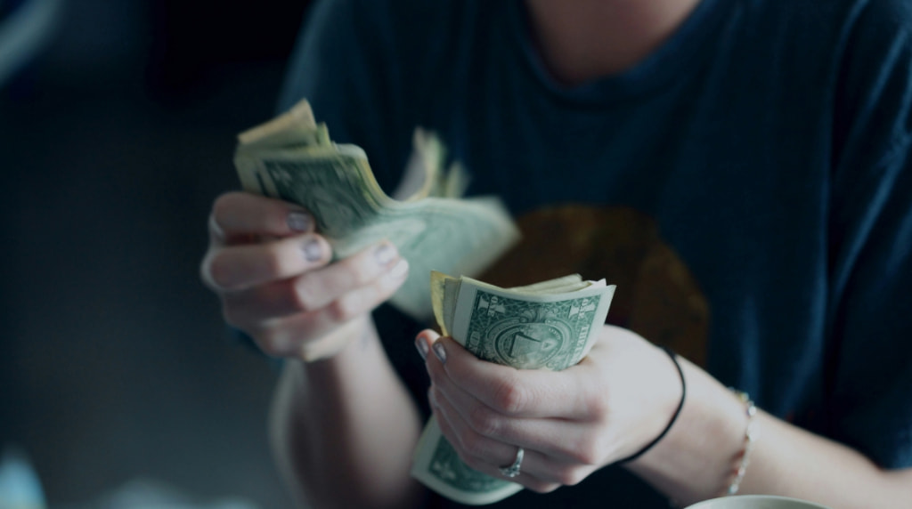 A person counting small dollar bills